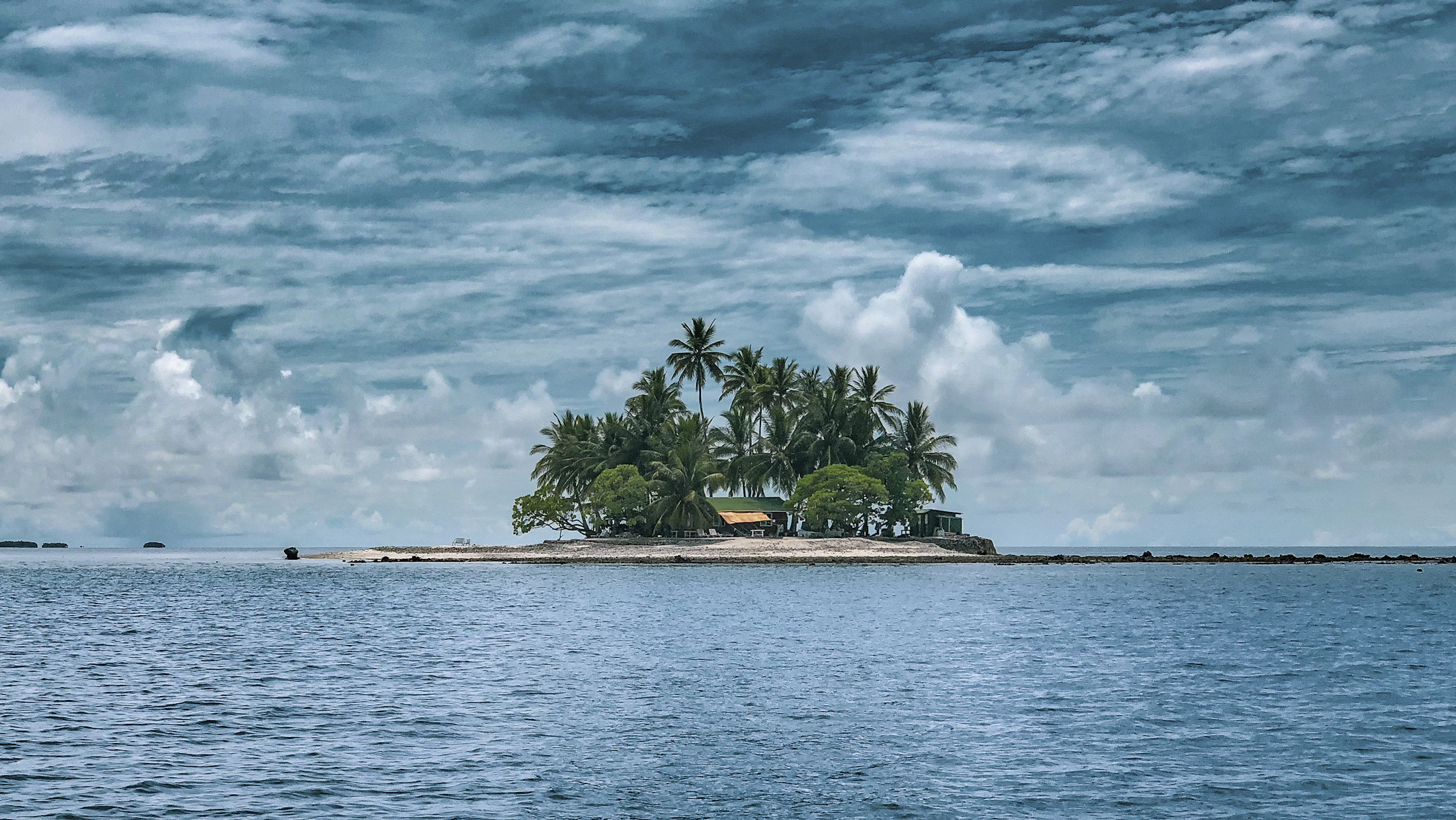 A small Pacific island beneath a wide blue sky